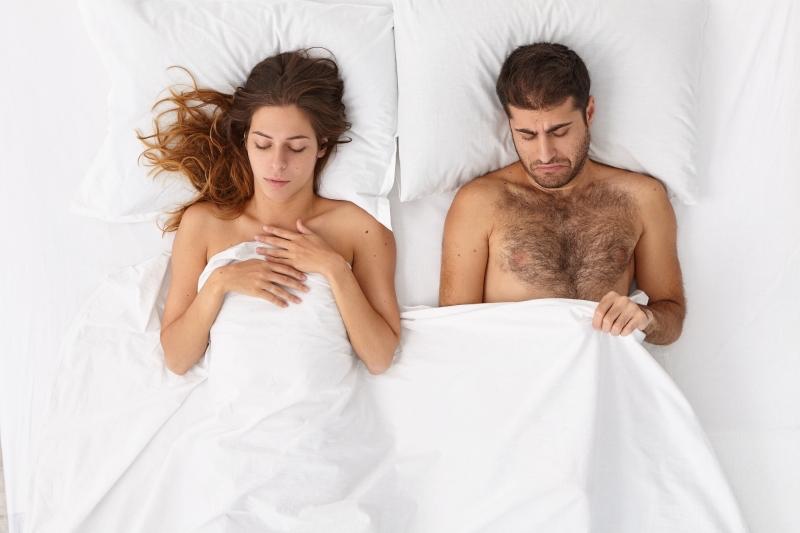 unhappy couple in bed with the man worried about priapism