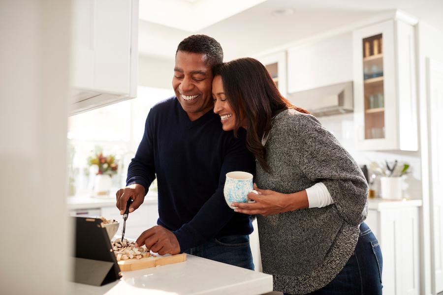 married couple happily cooking together at home