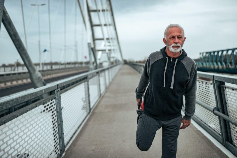 elderly man jogging over a bridge