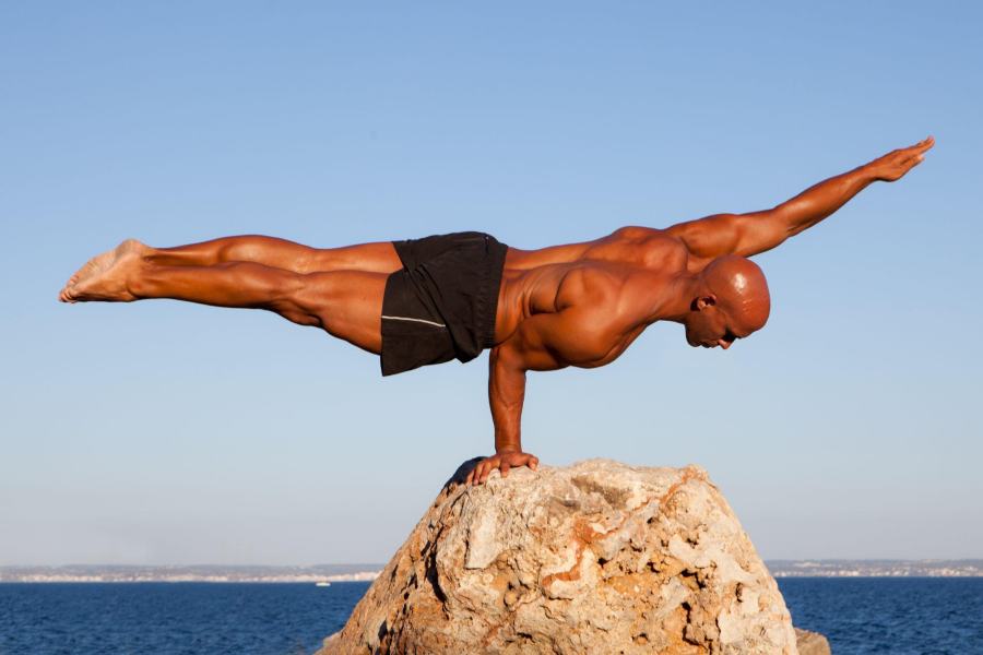 fit man balancing on one hand on a rock