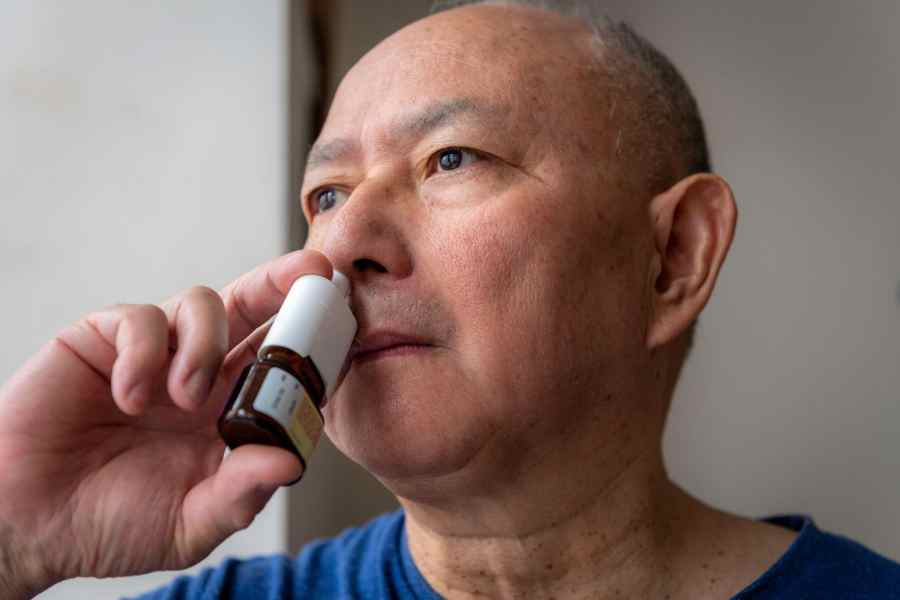 middle-aged man inhaling medicine for seasonal allergies