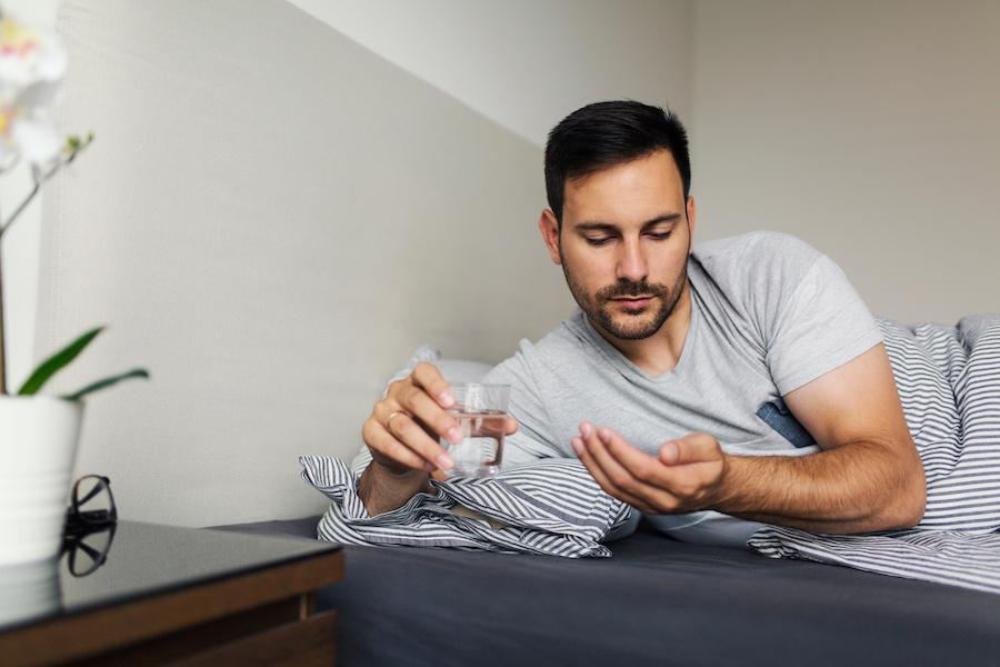 man taking a tadalafil pill in bed