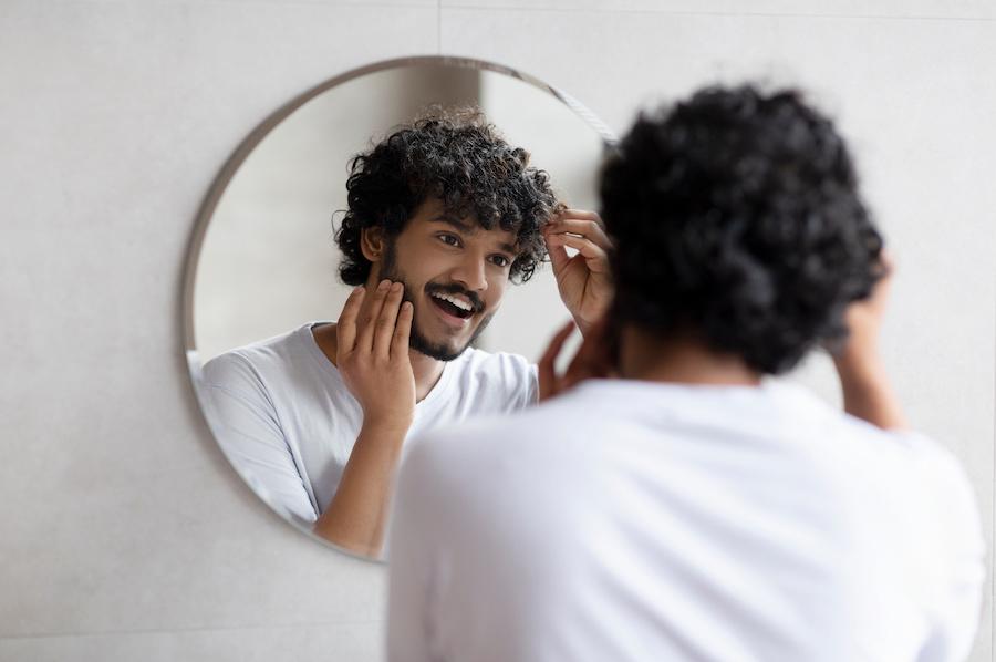 young man examining his hair in the mirror