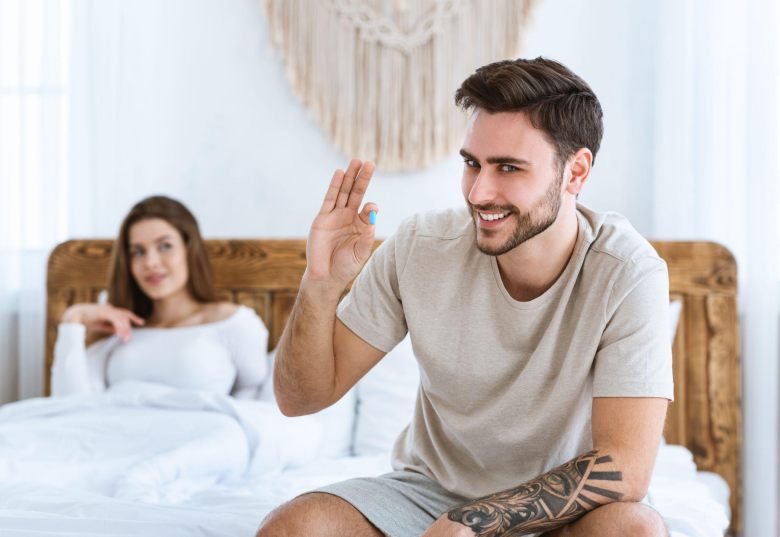 young man ready to take viagra while his girlfriend awaits in bed