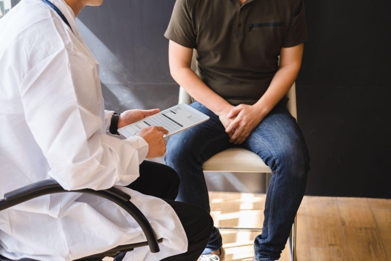 doctor filling out a chart while talking with a male patient