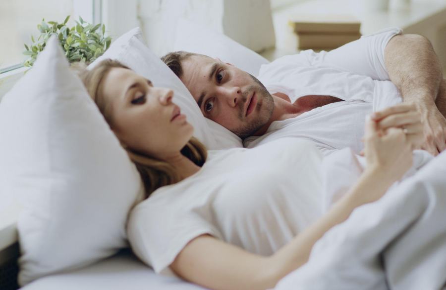 young couple in bed with the woman talking and the man listening attentively