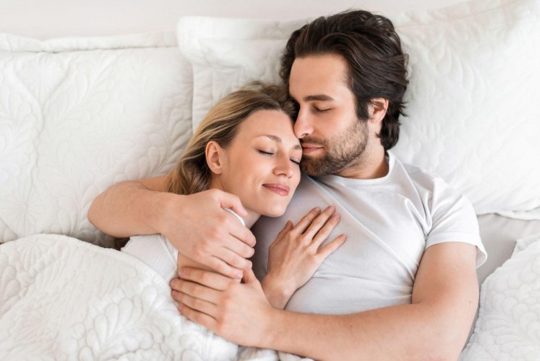 couple in bed embracing each other happily