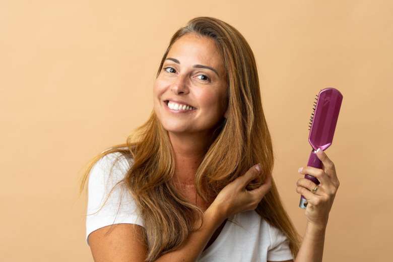 young woman smiling and combing her long hair