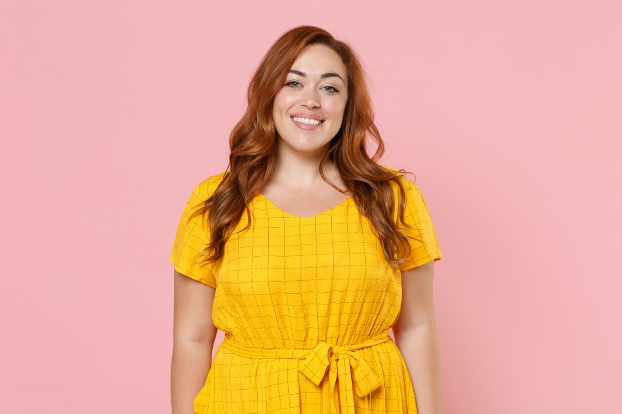 Smiling woman in yellow dress considering Wegovy vs. Zepbound