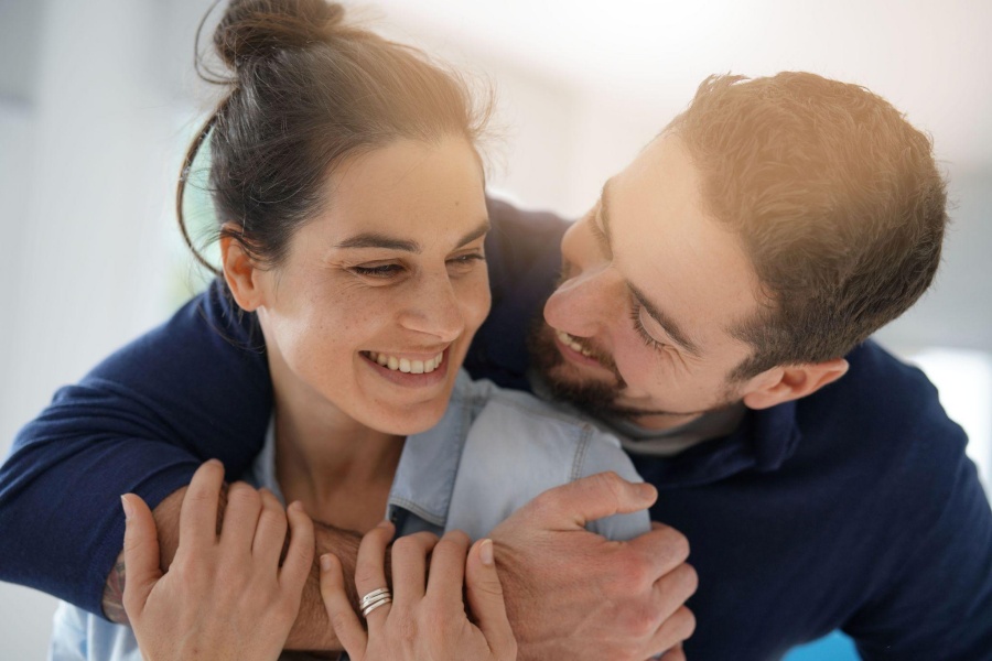 Happy couple embracing and smiling, man hugging woman from behind